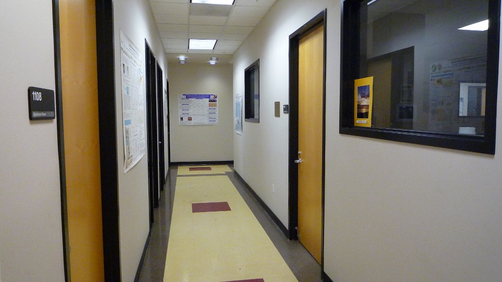 hallway with doors to offices and posters on the walls