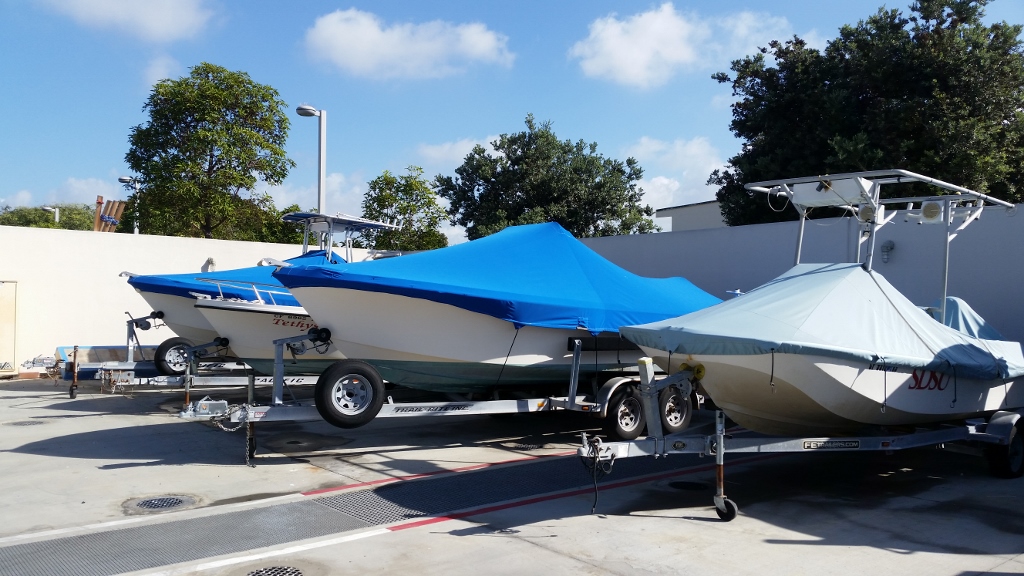 side view of 4 boats parked on a concrete lot